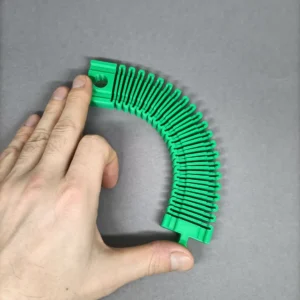 Mão a dobrar uma pista de comboios verde flexível impressa em 3D com formato de acordeão.