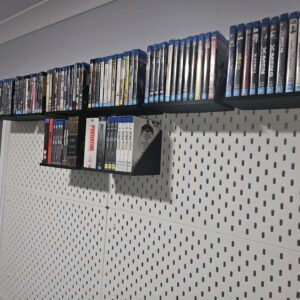 Painel IKEA Skadis com várias prateleiras pretas impressas em 3D, carregadas com uma grande coleção de dezenas de filmes Blu-ray organizados verticalmente.