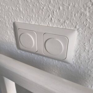 Protetor de tomadas branco com textura para segurança infantil.